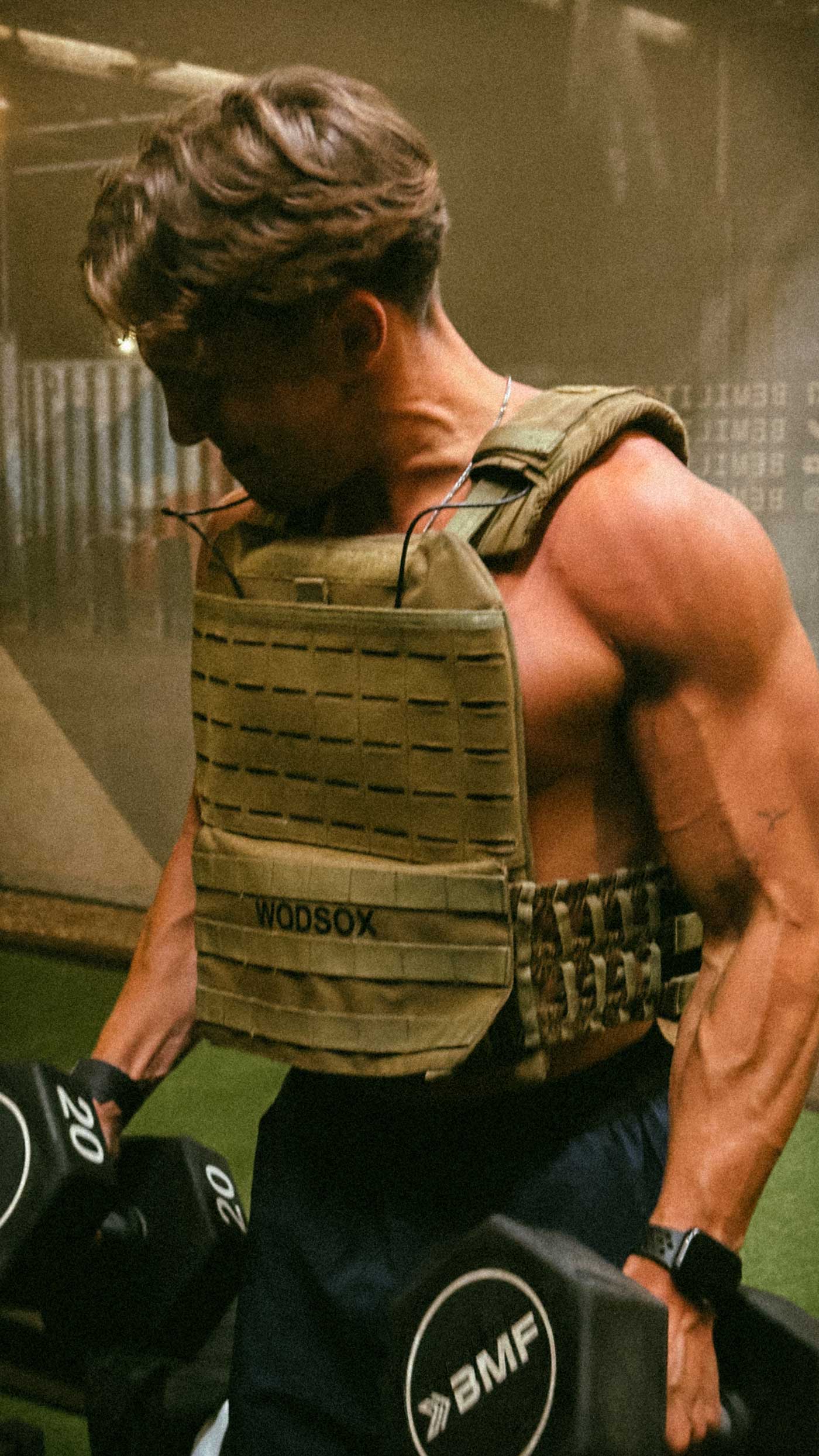 Coach is posing shirtless in front of an urban gym.